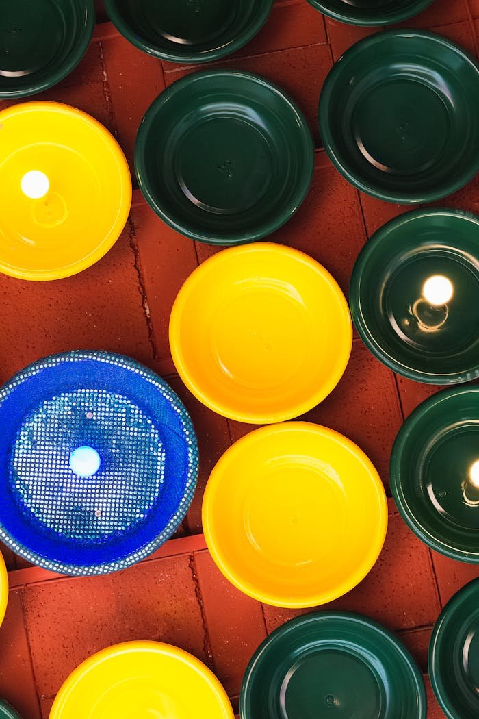 Vibrant yellow, green, and blue plastic bowls displayed on a red background in a geometric pattern.